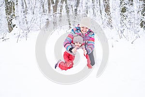 Mother and daughter on winter walk in nature. woman and child girl make snowman