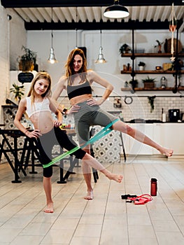 Mother and daughter working out at home doing resistance band leg exercise