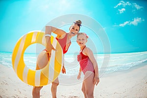 Mother and daughter with yellow inflatable lifebuoy on beach