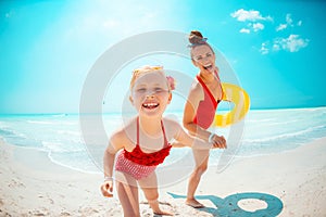 Mother and daughter with yellow inflatable lifebuoy on beach