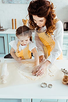 Mother and daughter in yellow polka dot aprons using dough molds