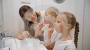 Mother and daughters brushing teeth together