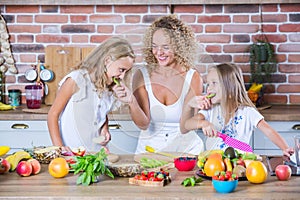 Mother and daughters cooking together in the kitchen. Healthy food concept.