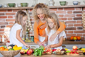 Mother and daughters cooking together in the kitchen. Healthy food concept.