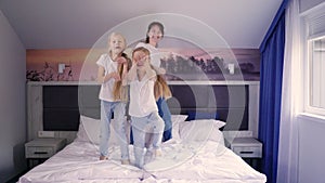 Mother and daughters jumping on bed