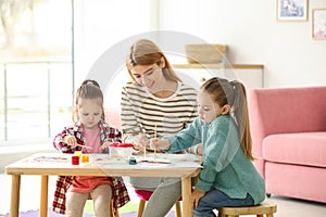 Mother and daughters painting at table. Playing with children