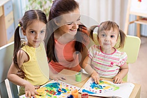 Mother and daughters are painting together. Happy family are coloring with paintbrush. Woman and children have a fun