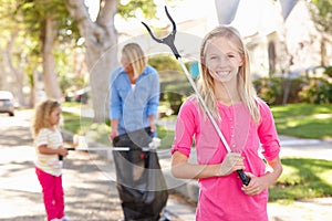 Mother And Daughters Picking Up Litter In Suburban Street