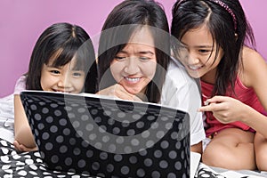 Mother and daughters playing with laptop