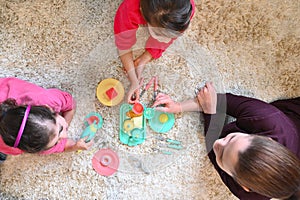 Mother and daughters playing together having a tea party