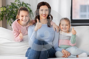 mother and daughters showing thumbs up at home