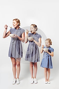 mother and daughters in similar dresses eating cereal breakfast together