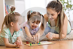 Mother and daughters sitting in a playroom, playing a ludo game and enjoying their time together