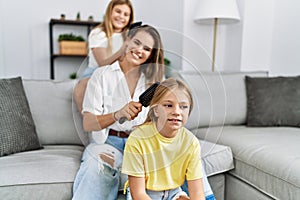 Mother and daughters smiling confident combing hair at home