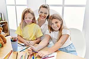 Mother and daughters smiling confident drawing at home