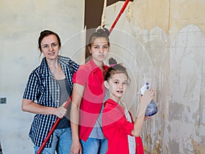 Mother and daughters together make repairs in the apartment, and stripped from the walls of the old Wallpaper.