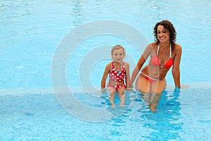 Mother and daugther sitting in open pool photo