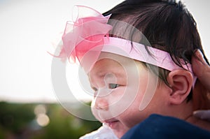 Mother day bonding concept with newborn baby nursing. Mother is holding newborn baby with flower pink headband with blue sky.