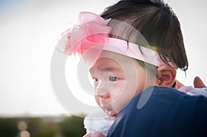 Mother day bonding concept with newborn baby nursing. Mother is holding newborn baby with flower pink headband with blue sky.