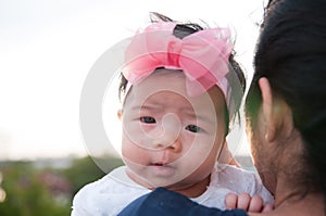 Mother day bonding concept with newborn baby nursing. Mother is holding newborn baby with flower pink headband with blue sky.