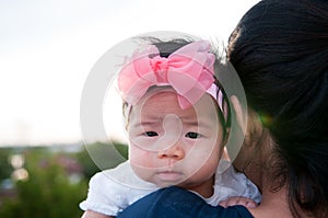 Mother day bonding concept with newborn baby nursing. Mother is holding newborn baby with flower pink headband with blue sky.