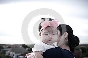 Mother day bonding concept with newborn baby nursing. Mother is holding newborn baby with flower pink headband with blue sky.