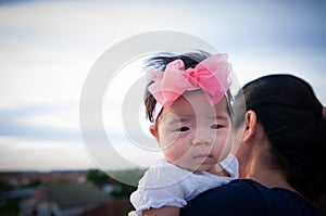 Mother day bonding concept with newborn baby nursing. Mother is holding newborn baby with flower pink headband with blue sky.