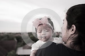 Mother day bonding concept with newborn baby nursing. Mother is holding newborn baby with flower pink headband with blue sky.