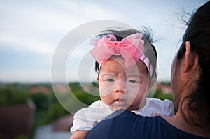 Mother day bonding concept with newborn baby nursing. Mother is holding newborn baby with flower pink headband with blue sky.