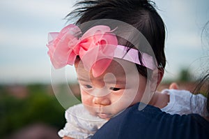 Mother day bonding concept with newborn baby nursing. Mother is holding newborn baby with flower pink headband with blue sky.