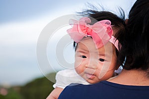 Mother day bonding concept with newborn baby nursing. Mother is holding newborn baby with flower pink headband with blue sky.