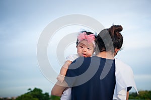 Mother day bonding concept with newborn baby nursing. Mother is holding newborn baby with flower pink headband with blue sky. Focu