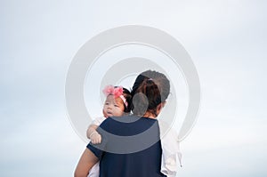 Mother day bonding concept with newborn baby nursing. Mother is holding newborn baby with flower pink headband with blue sky. Focu