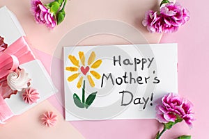 Mother day greeting card on pink background. Text Happy Mothers day. Breakfast, carnation gift and a postcard made by