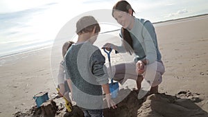 Mother Digging With Children on the Beach