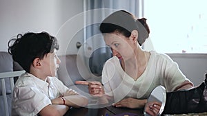 mother discussing misbehavior with tween son while they sitting at home table