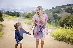 Mother and diverse son walking together holding hands outdoors at a hillside park near Los Angeles California