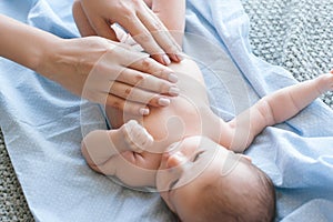 Mother does a body massage to a newborn baby