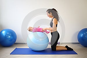 Mother doing gymnastics with a baby on fitball in photo