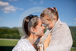 Mother drying daughter with towwl outdoors after swimming.