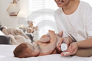 Mother with dusting powder near her cute baby at home, closeup. Space for text