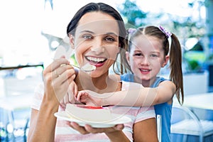 Mother eating a piece of cake with her daughter