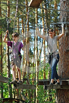 Mother and eight year old son surmounting obstacle course in the outdoor woodland rope park. Active family rest photo