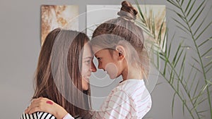 Mother embraces her daughter in the bedroom. Children bring joy and coziness to the home. Parental hugs fill the day with