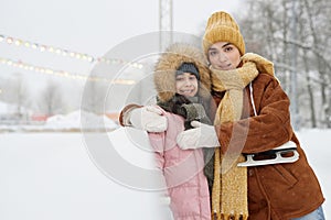 Mother Embracing Daughter Standing By Skating Rink photo