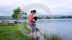 Mother enjoying with her child. Happy asian girl having fun at lake
