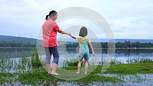 Mother enjoying with her child. Happy asian girl having fun at lake.