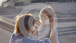 Mother escorts her son to school. A mother puts on a protective mask for her son before entering the school. The