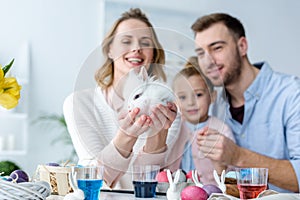 Mother with family holding cute bunny by table