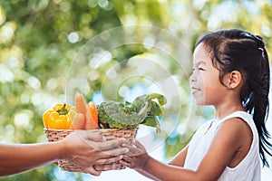 Mother farmer hand giving basket of vegetables to little child